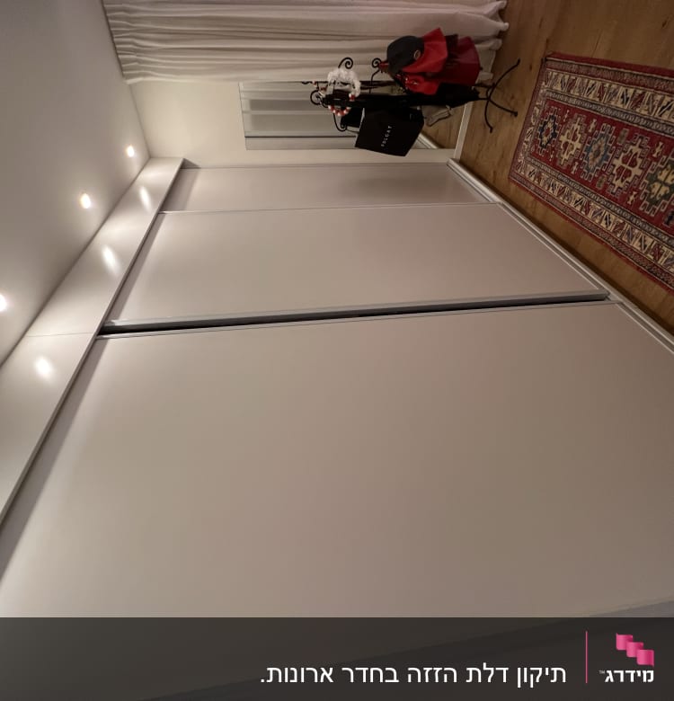 ארון לבן עם דלתות הזזה ותאורה עליונה